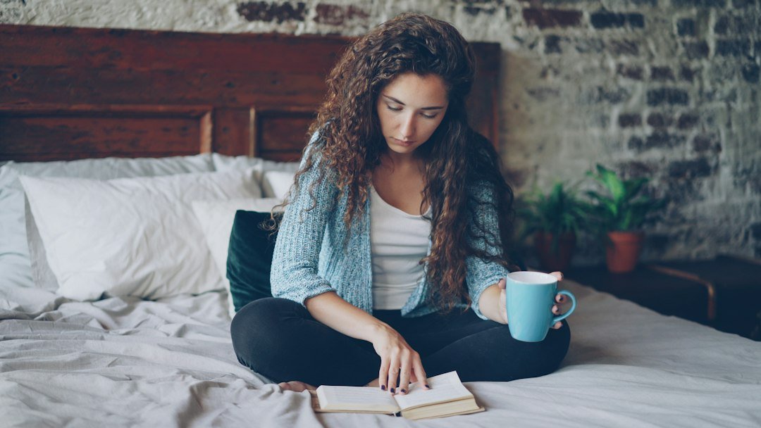 Woman reading a book at home with a warm drink